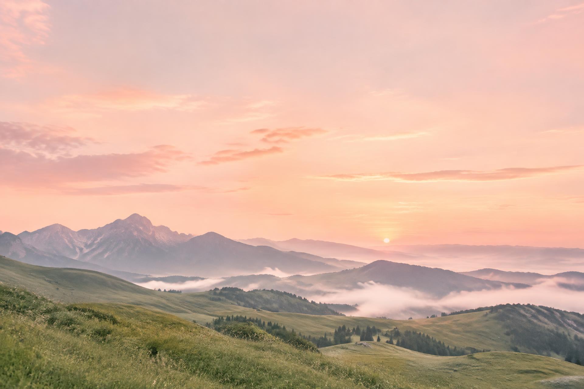 A peach sunrise over peaceful mountain meadows